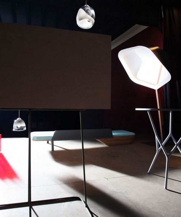 Композиция из бытовых предметов: настольная лампа, подвесные светильники, стол с ажурными ножками, деревянная кушетка и рабочий стол