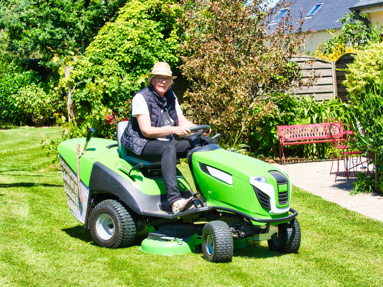 Mature woman gardening on tractor cutting grass