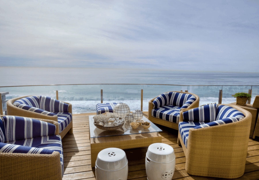 Оформление террасы загородного дома с видом на море - мягкие плетёные кресла и стол